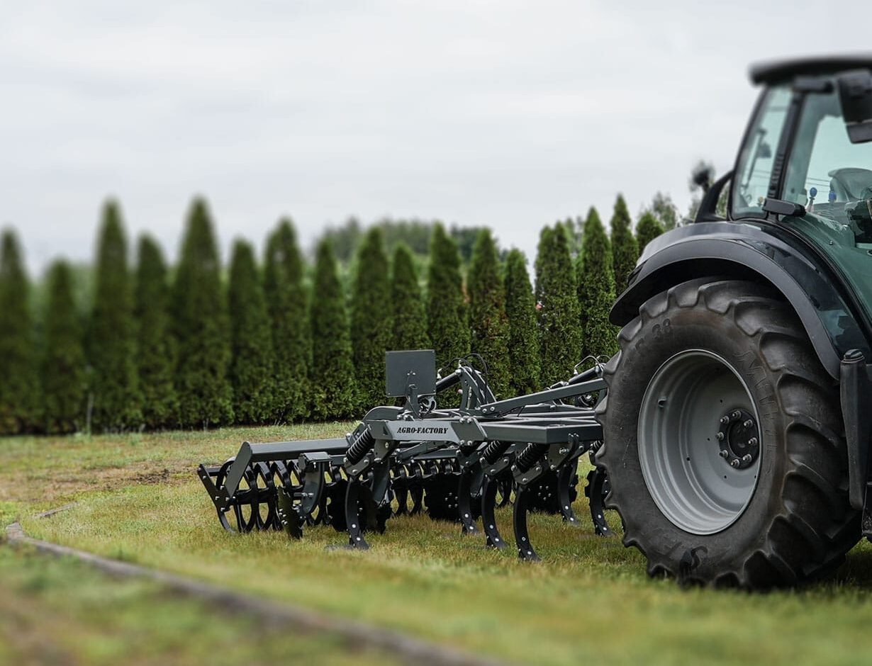 Maszyna rolnicza do orki Agro-Factory 2podłączona do traktora, gotowa do pracy w polu, widok z boku.