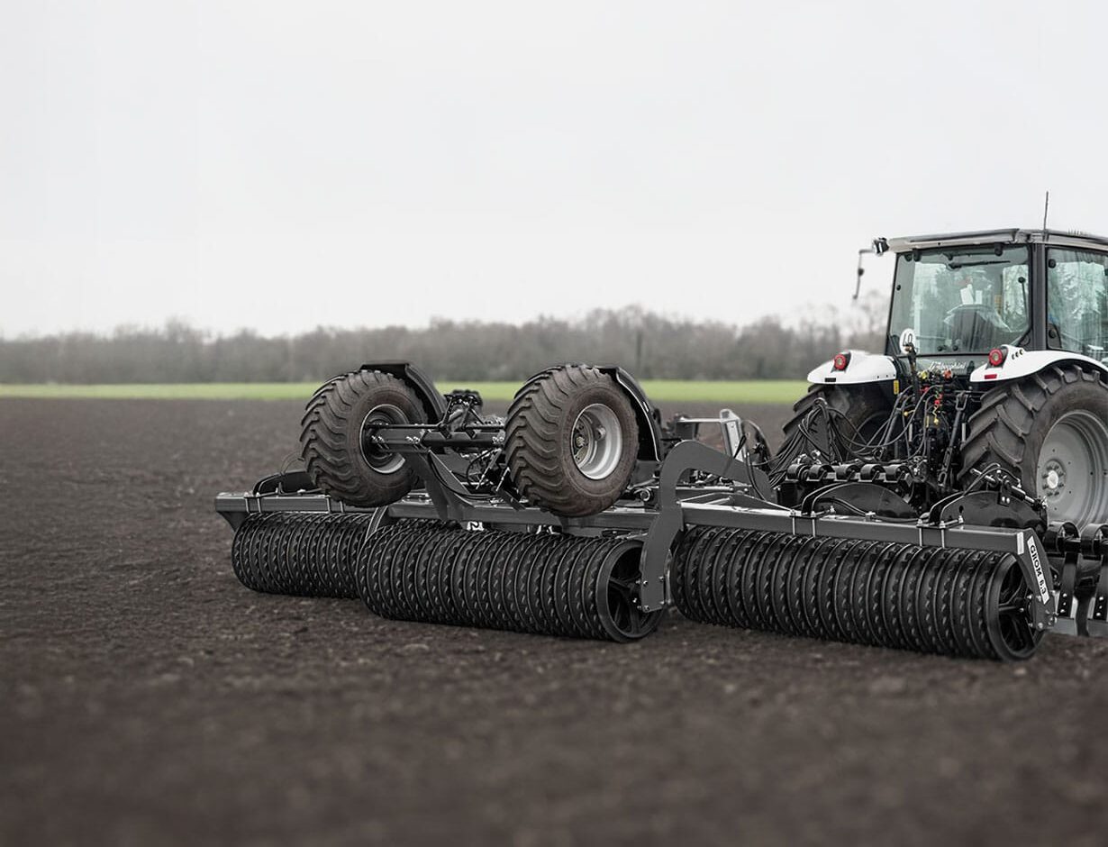Wały uprawowe / wały posiewne Agro-Factory 2– nowoczesna maszyna rolnicza podczas pracy w polu, ciągnięta przez traktor, zapewniająca wyrównanie i zagęszczenie gleby.